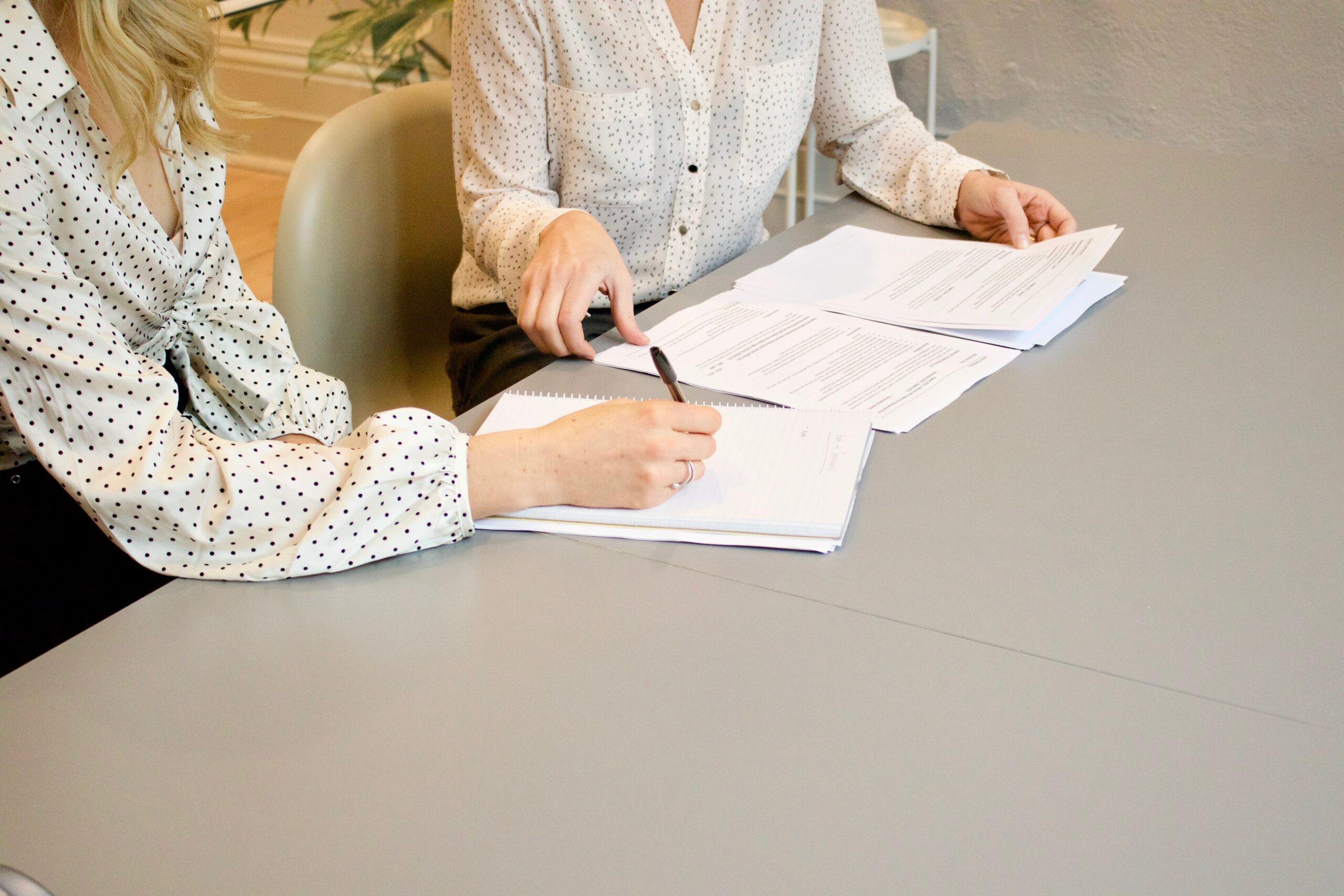 Two women sitting at a table signing a lease agreement.