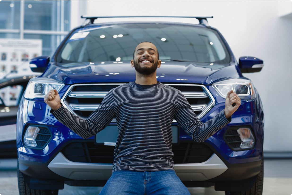 A man sitting on the floor leasing a blue ford escape.