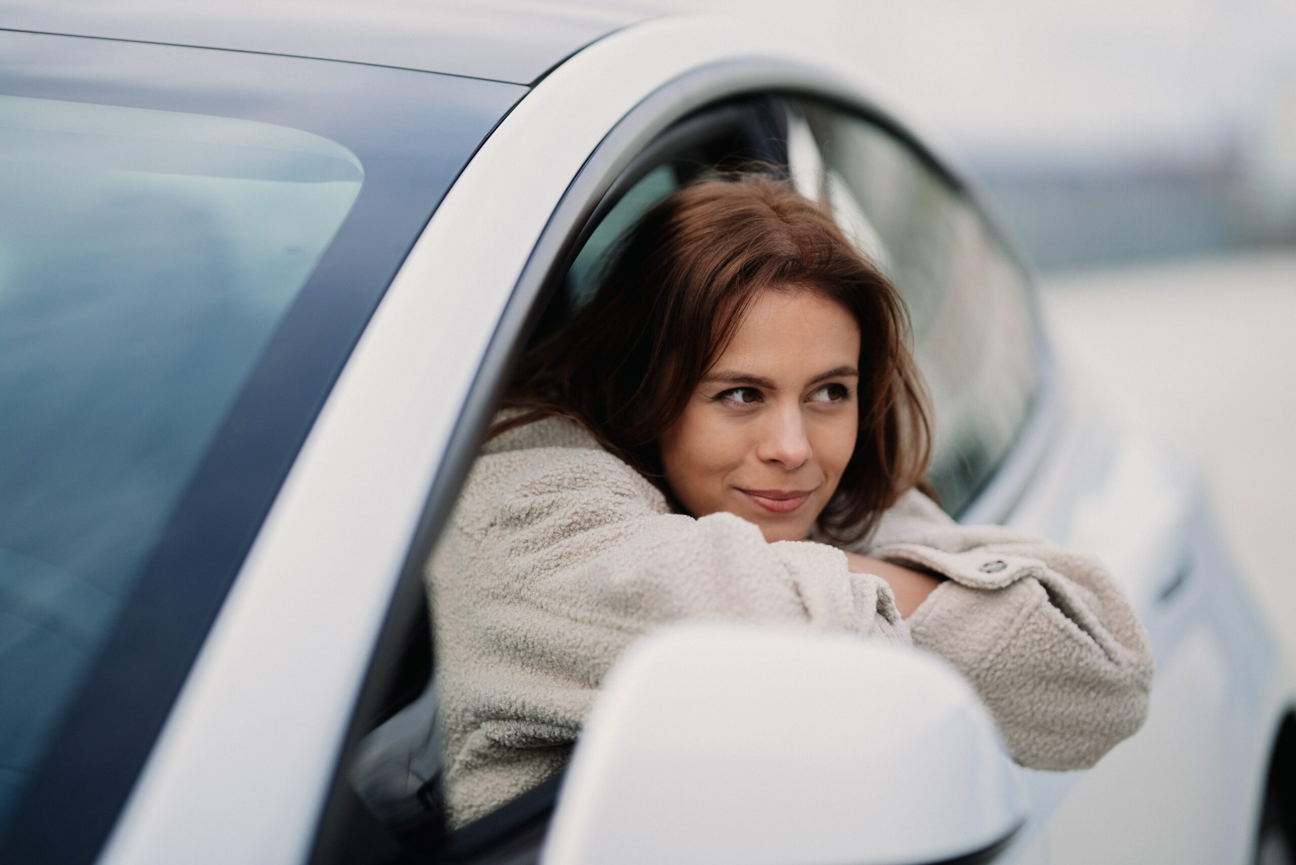 A woman leaning out of the window of a car, enjoying the freedom of a lease.