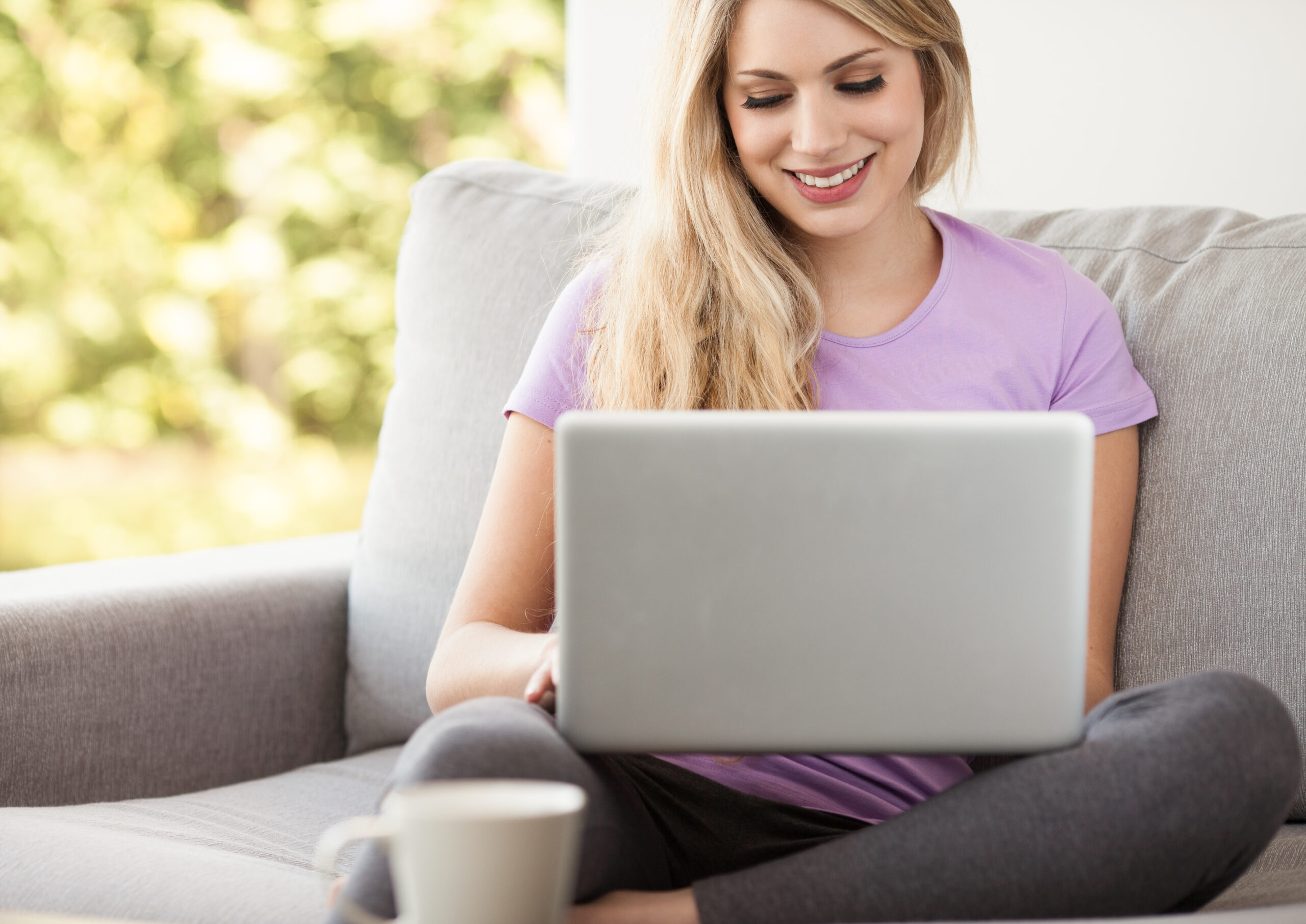 A woman using a laptop on a couch.