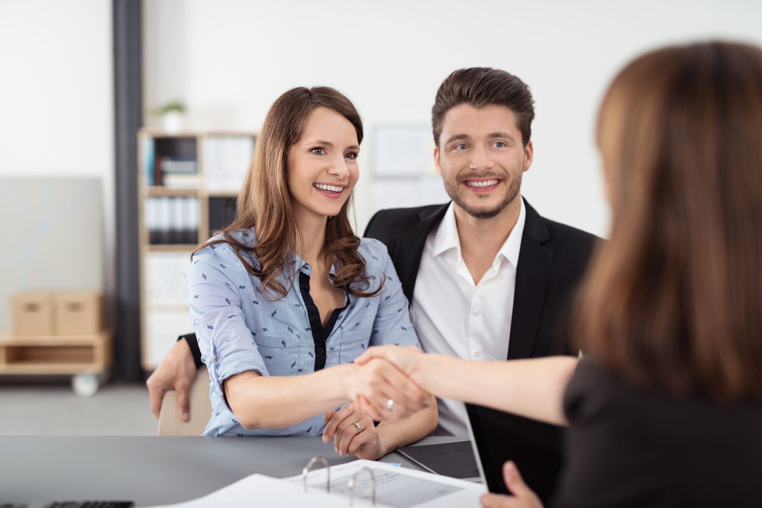 Two people shaking hands in an office after finalizing a lease agreement.